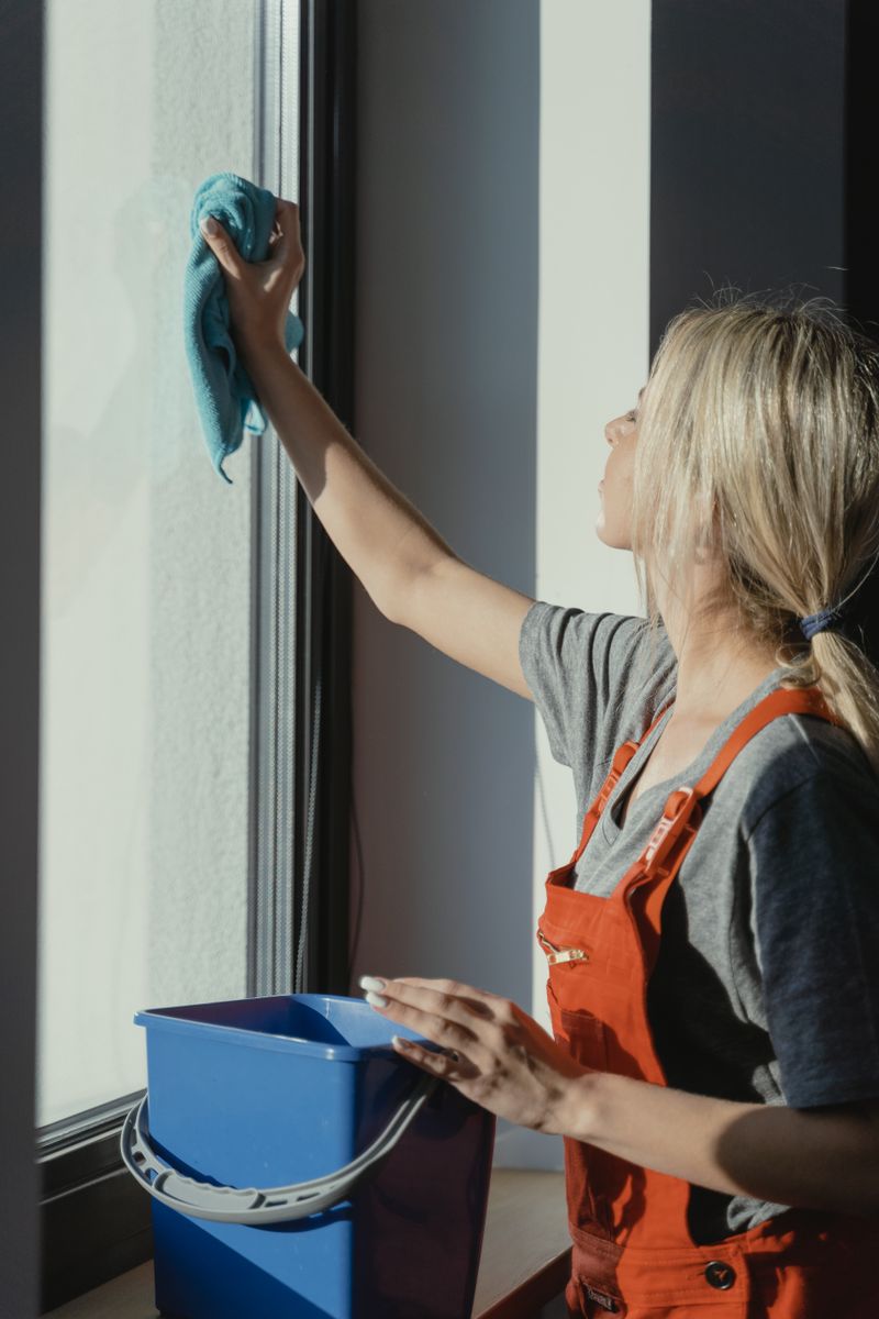 Cleaner wiping down interior glass on a scheduled recurring visit.